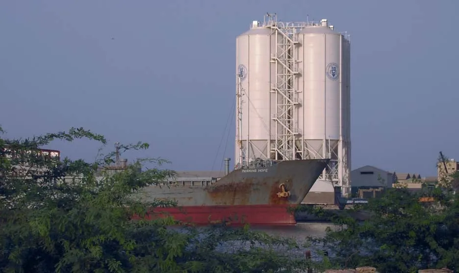 Vier Zementsilos mit Treppenturm am Pier von Port Sudan, davor ein Frachtschiff