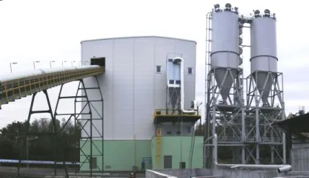 Zwei Silos auf Stützgerüst neben einem verkleideten Anlagengebäude